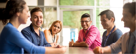 Group of colleagues smiling during a team meeting in a bright office space.