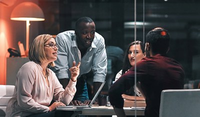 Group of four diverse professionals having a late-night meeting in a modern office.