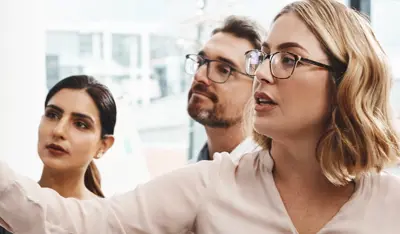 Professionals planning business strategies on a writable wall.