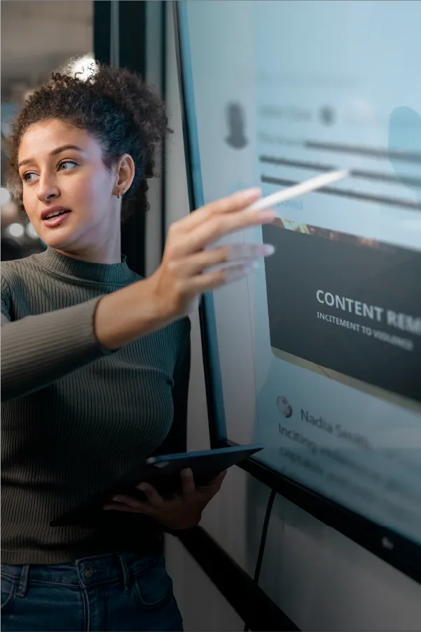 Professional reviewing content on a digital screen using a stylus and tablet.