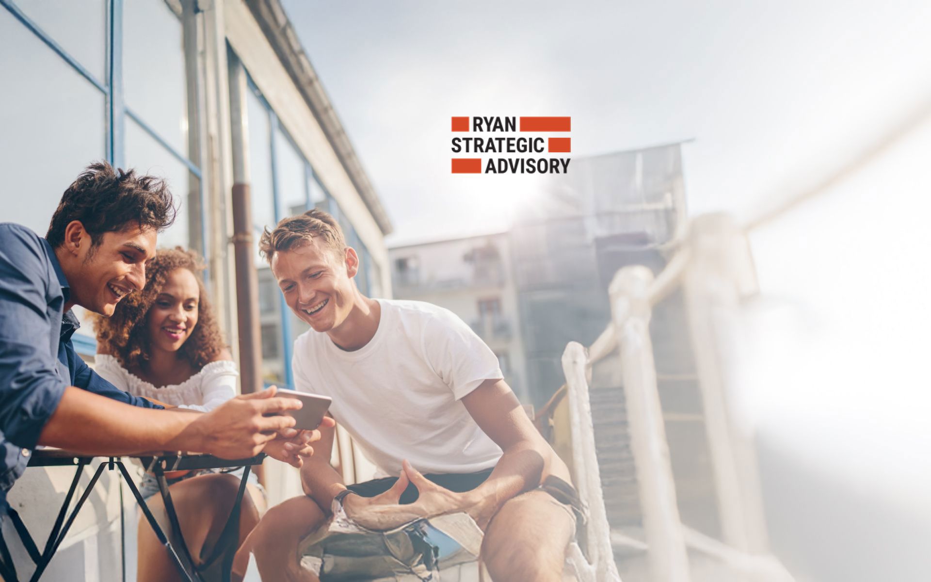 Group of friends, consisting of two boys and a girl, sitting outdoors watching videos on a phone