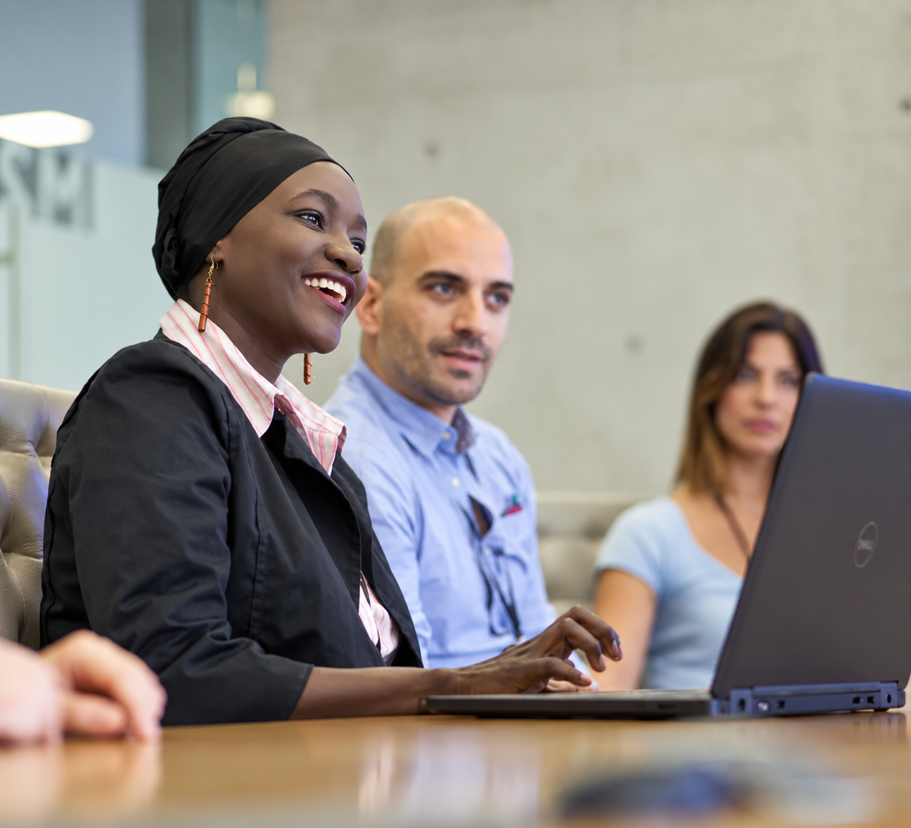 A diverse team collaborating in a meeting with a colleague using a laptop.