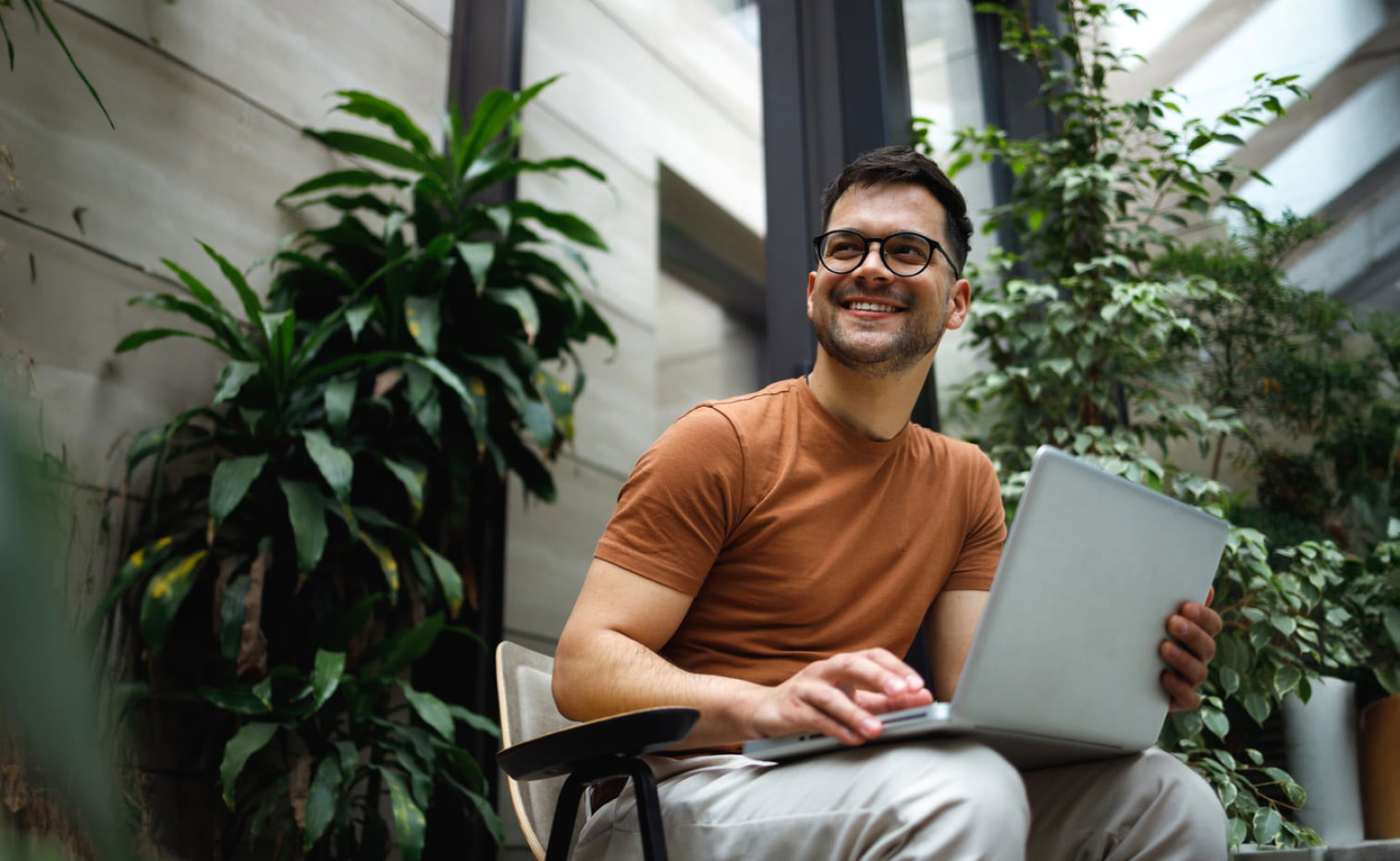 Smiling young man working on his laptop on a modern green office