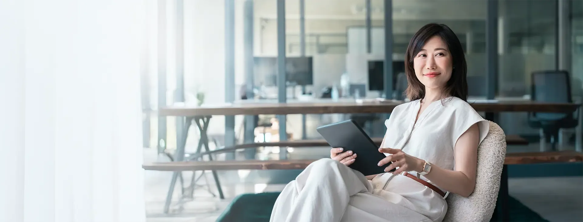 Asian businesswoman reading comfortably on her tablet..