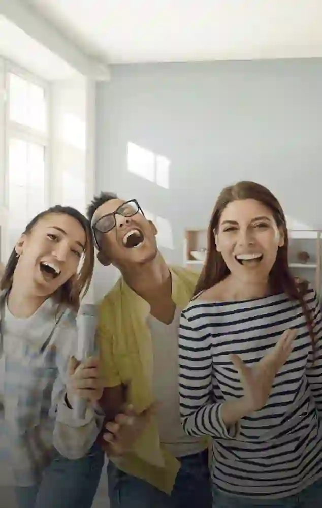 Three people sing joyfully together; one holds a microphone. sunlight streams through large windows, illuminating their cheerful expressions in a bright, airy room.